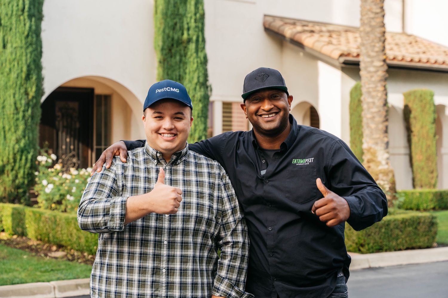 AMárquez Agency team member with a trades client, both giving a thumbs up outside a finished job.